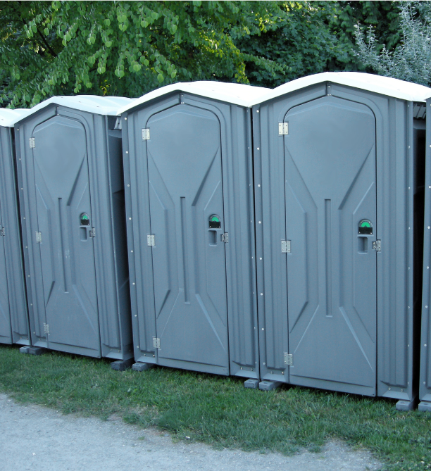 A picture of three Portable Toilets lined up next to each other.
